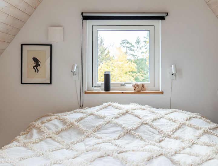 En bild på ett sovrum med fönstret öppet